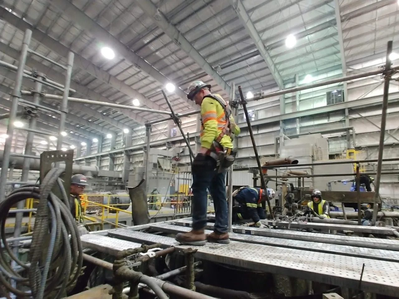 A man in yellow vest standing on top of metal platform.