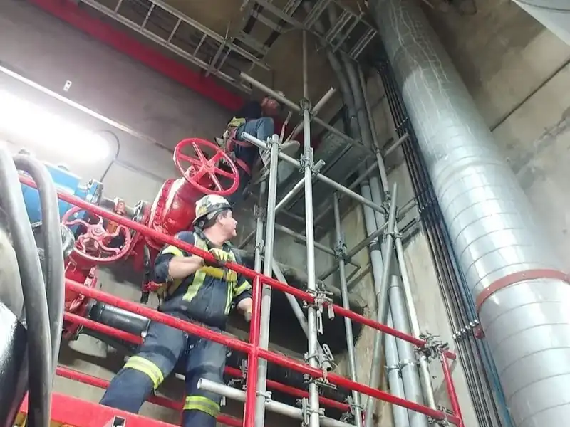 A man in a fire station on some scaffolding.