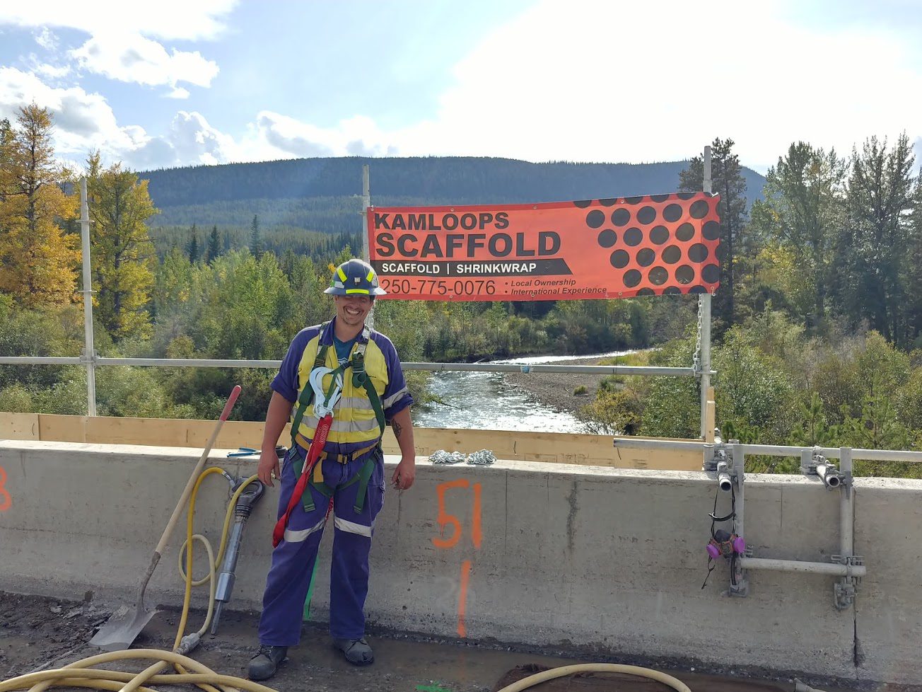 A man standing next to a bridge with ropes.