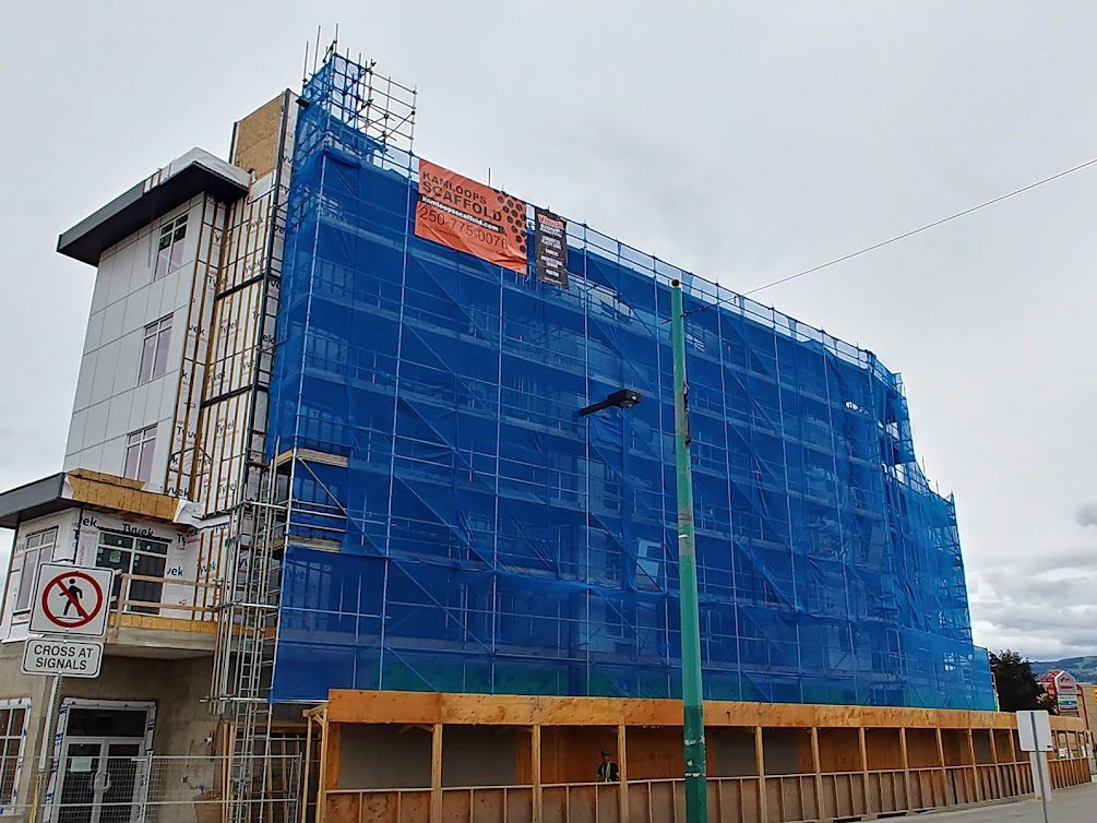 A building with scaffolding around it and a blue tarp covering the side of it.