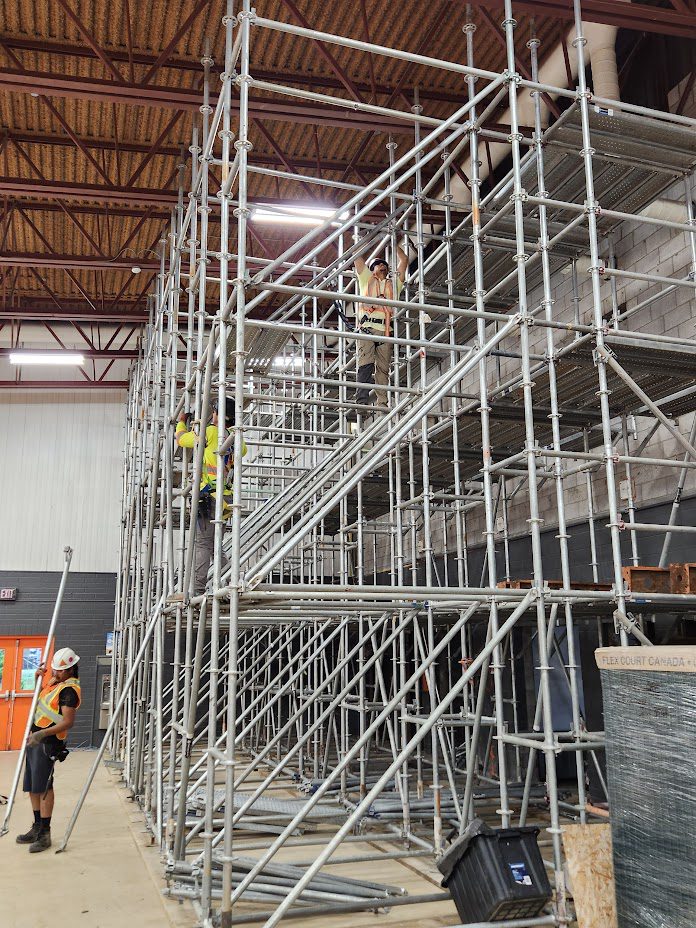 A man standing on top of scaffolding in an industrial building.