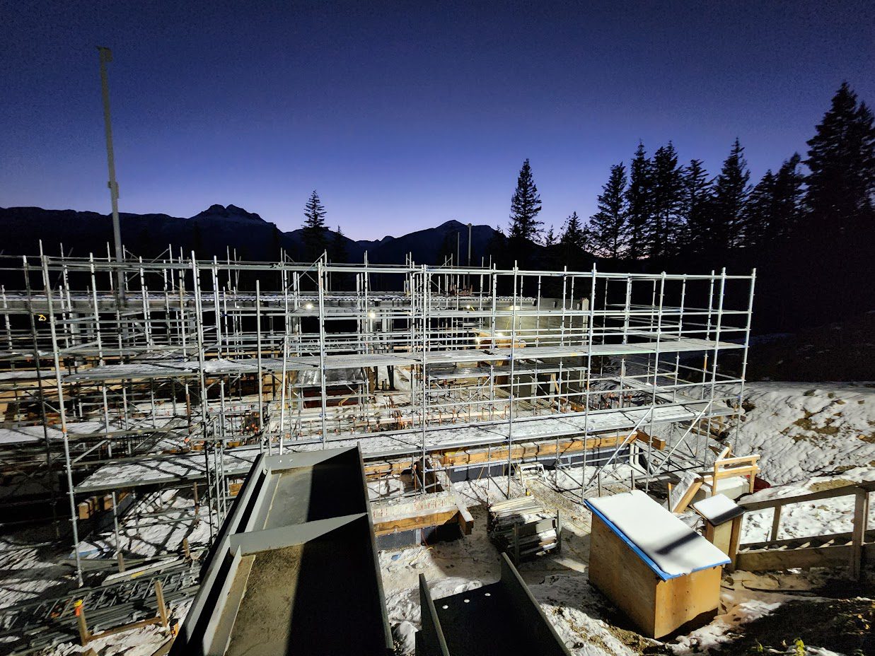 A construction site with scaffolding and trees in the background.